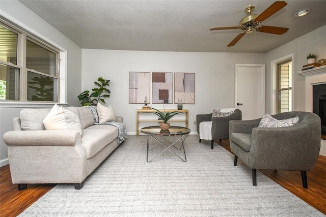 living room with baseboards, recessed lighting, a fireplace, wood finished floors, and a ceiling fan