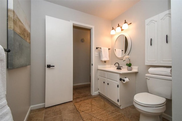 bathroom with toilet, vanity, tile patterned floors, and baseboards