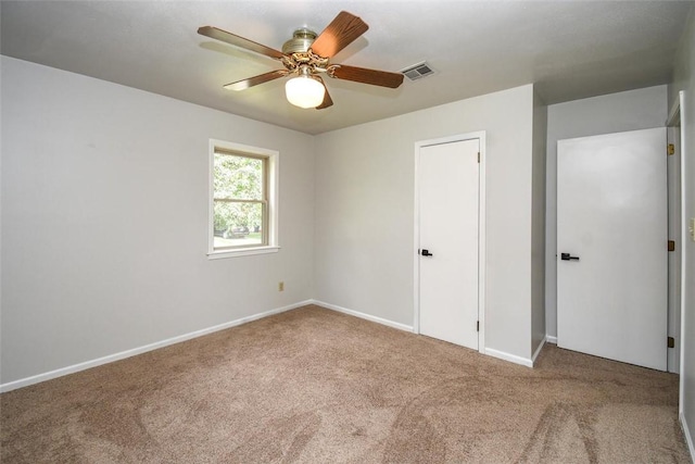 carpeted empty room with baseboards, visible vents, and ceiling fan