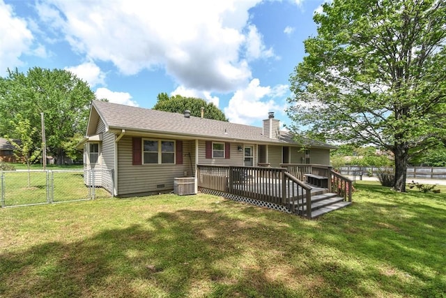 rear view of house featuring fence, a chimney, a yard, and a wooden deck