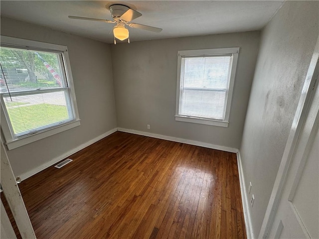 empty room featuring visible vents, baseboards, ceiling fan, and dark wood-type flooring