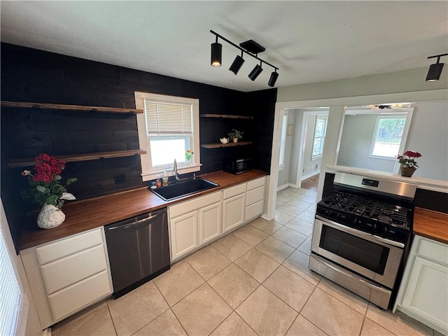 kitchen with open shelves, a sink, stainless steel appliances, butcher block countertops, and rail lighting