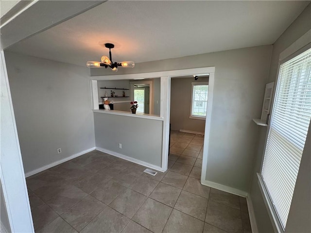 unfurnished room featuring visible vents, a notable chandelier, tile patterned floors, and baseboards