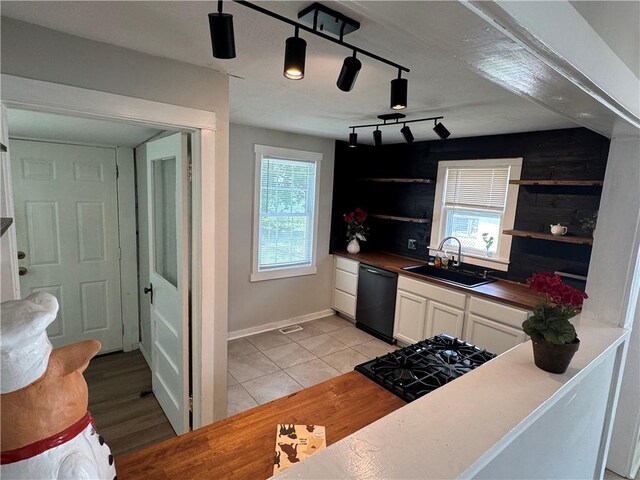 kitchen with a sink, black dishwasher, light tile patterned floors, open shelves, and white cabinets