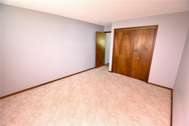 unfurnished bedroom featuring baseboards, a textured ceiling, a closet, and carpet flooring