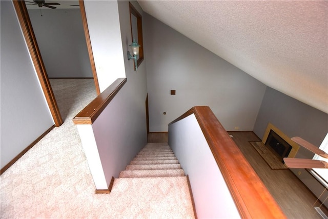staircase featuring carpet flooring, a ceiling fan, a textured ceiling, and lofted ceiling