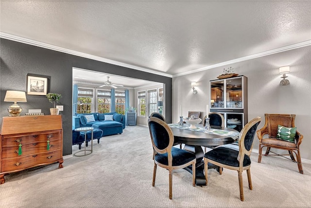dining space with carpet flooring, ceiling fan, crown molding, baseboards, and a textured ceiling