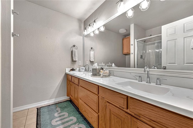bathroom with tile patterned floors, baseboards, a stall shower, and a sink