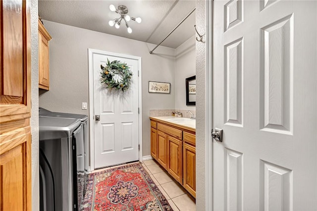 laundry room featuring light tile patterned floors, washer and dryer, cabinet space, and a sink