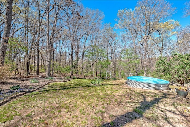 view of yard featuring a swimming pool and a forest view