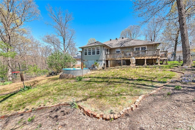 rear view of house featuring a lawn, a jacuzzi, and a wooden deck