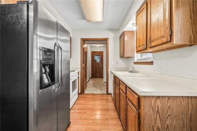 1622 2nd St, Westville, OK 74965 - kitchen with brown cabinets, a sink, light wood-style floors, light countertops, and white appliances