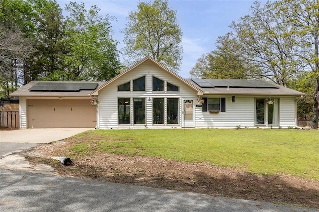 view of front of property with concrete driveway, a front yard, and solar panels