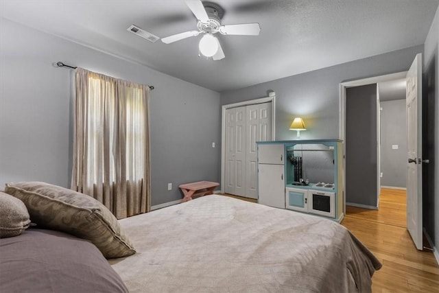 bedroom with ceiling fan, visible vents, baseboards, a closet, and light wood-type flooring