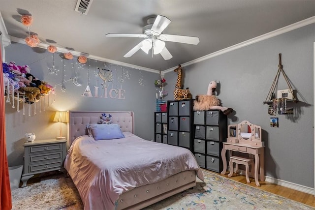 bedroom featuring crown molding, a ceiling fan, visible vents, baseboards, and wood finished floors