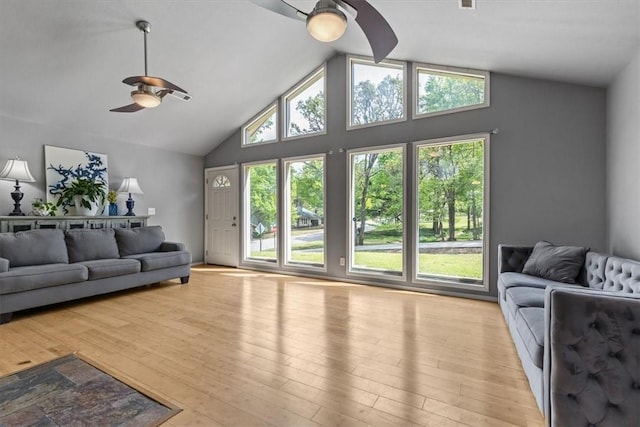 living area with high vaulted ceiling, ceiling fan, and light wood-style flooring