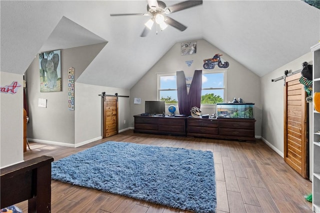 bedroom featuring wood finished floors, a barn door, and baseboards