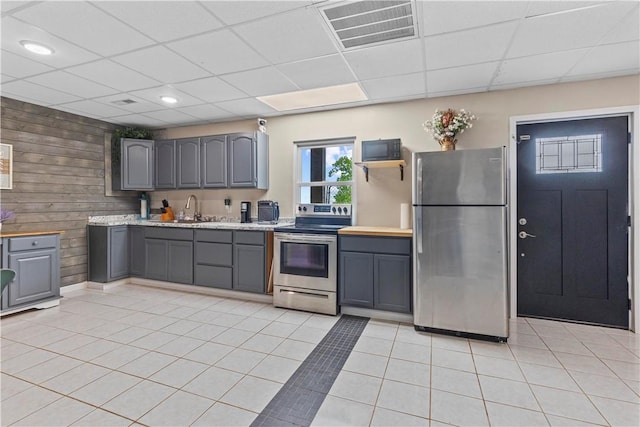 kitchen with a paneled ceiling, gray cabinets, stainless steel appliances, and visible vents