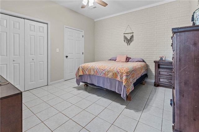 bedroom featuring light tile patterned floors, crown molding, a closet, brick wall, and a ceiling fan