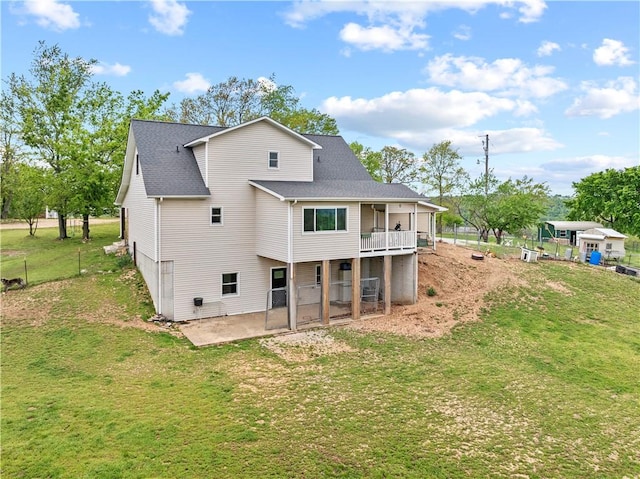 rear view of house with a patio, roof with shingles, and a lawn