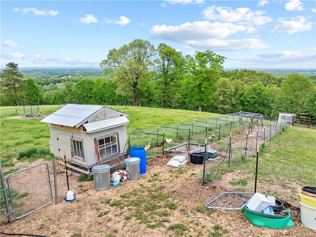 view of yard featuring a vegetable garden, fence, and a view of trees