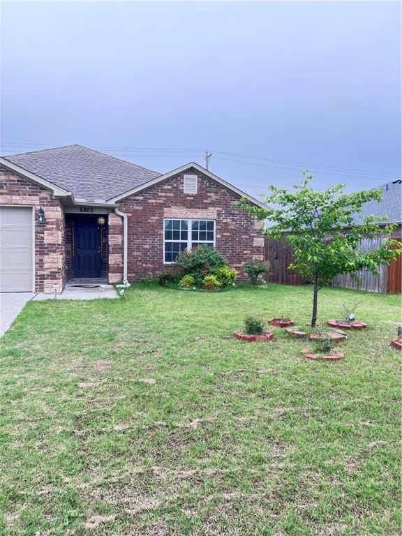 single story home with brick siding, fence, a shingled roof, a garage, and a front lawn