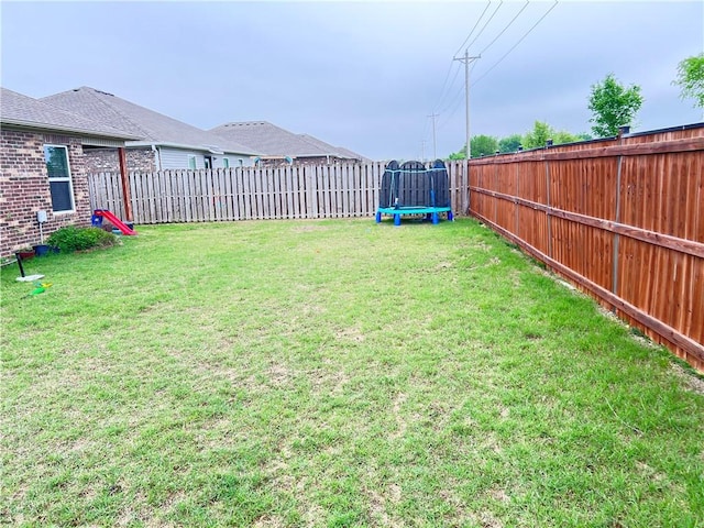 view of yard with a trampoline and a fenced backyard