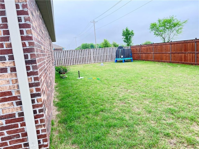view of yard featuring a trampoline and a fenced backyard