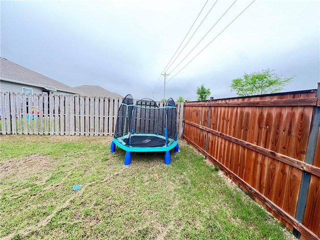view of yard with a trampoline and a fenced backyard