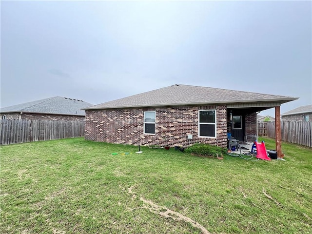 rear view of property with a lawn, brick siding, and a fenced backyard