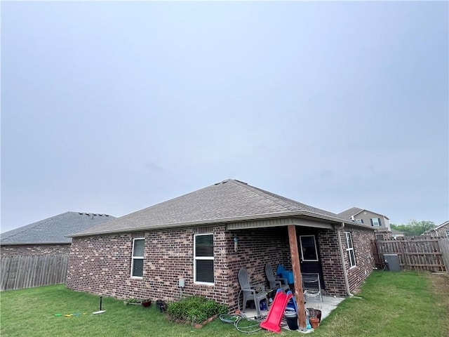 back of property with a yard, a patio, brick siding, and a fenced backyard