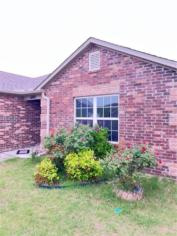 view of home's exterior with a lawn and brick siding