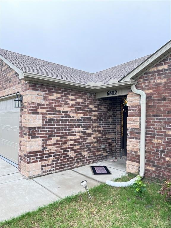 view of home's exterior with brick siding, an attached garage, and roof with shingles