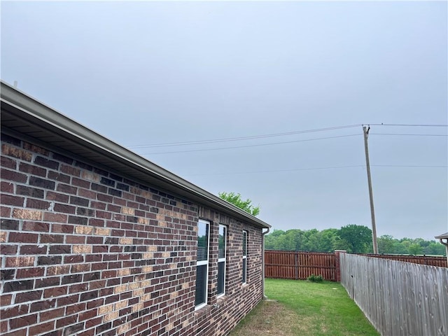 view of home's exterior featuring brick siding, a fenced backyard, and a lawn