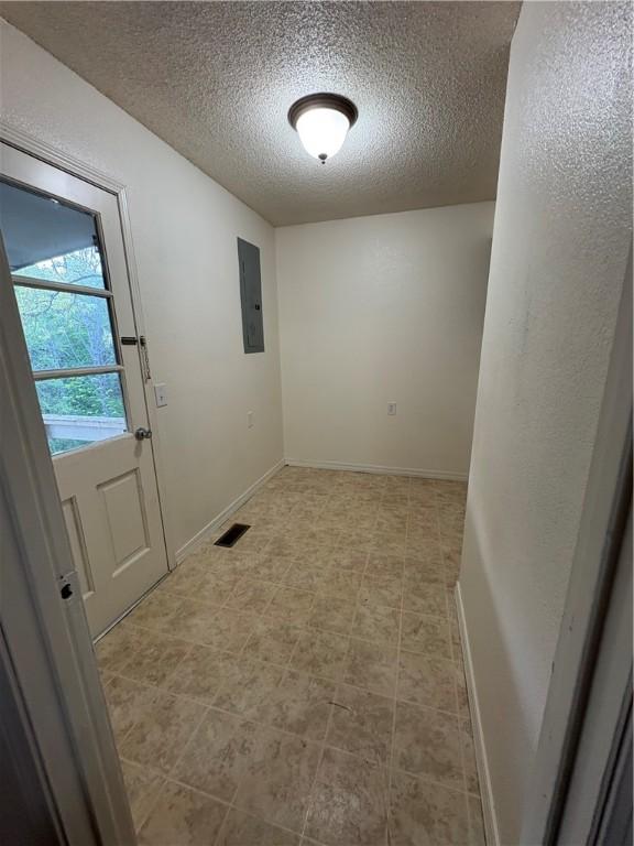 doorway to outside featuring a textured ceiling, visible vents, electric panel, and baseboards