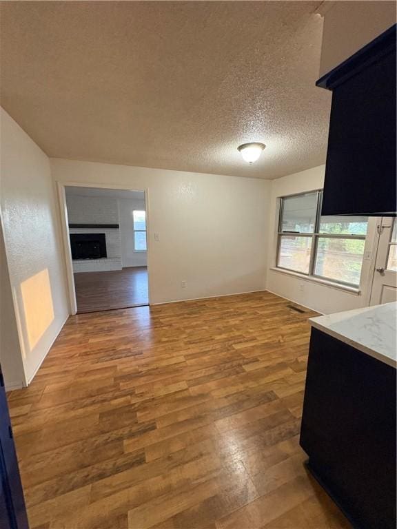 unfurnished dining area featuring wood finished floors, a textured ceiling, and a fireplace