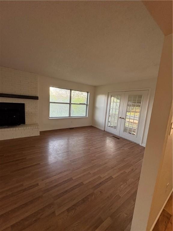 unfurnished living room featuring french doors, wood finished floors, and a fireplace