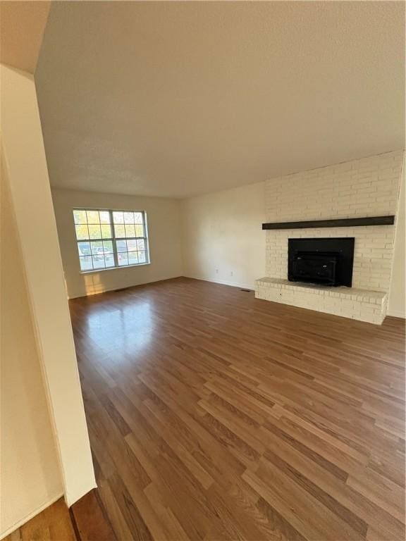 unfurnished living room featuring wood finished floors and a brick fireplace
