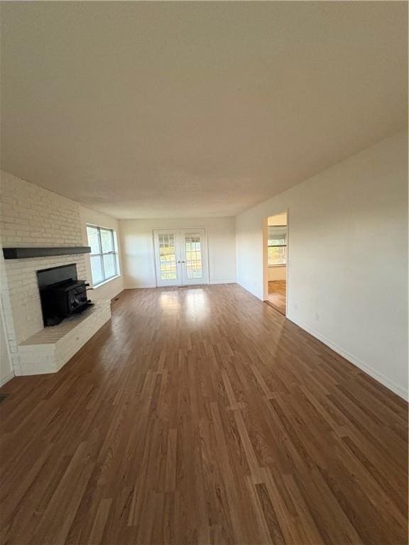 unfurnished living room featuring dark wood finished floors, baseboards, and a brick fireplace