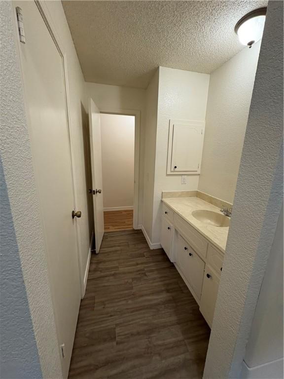 8455 Par Ln, Rogers, AR 72756 - bathroom with wood finished floors, a textured ceiling, vanity, and a textured wall