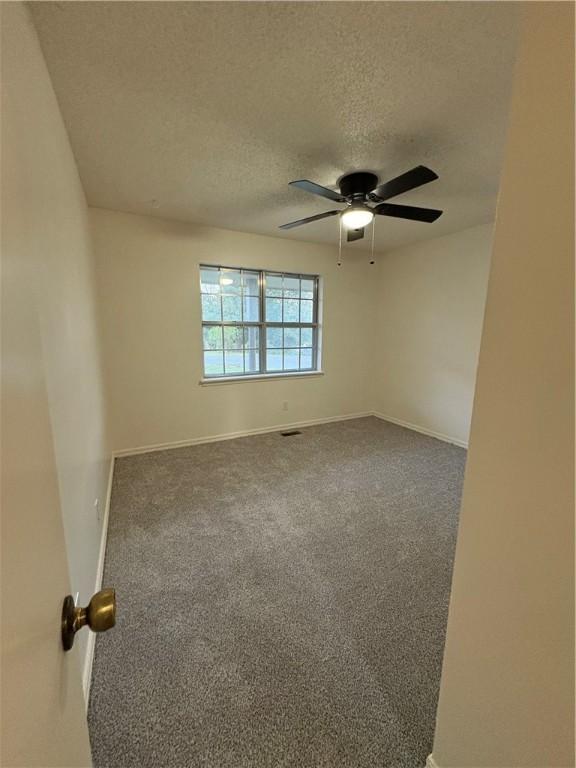 empty room with carpet flooring, a textured ceiling, a ceiling fan, and baseboards