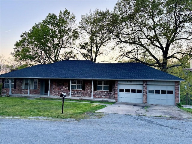 ranch-style house featuring a front yard, driveway, a garage, and brick siding