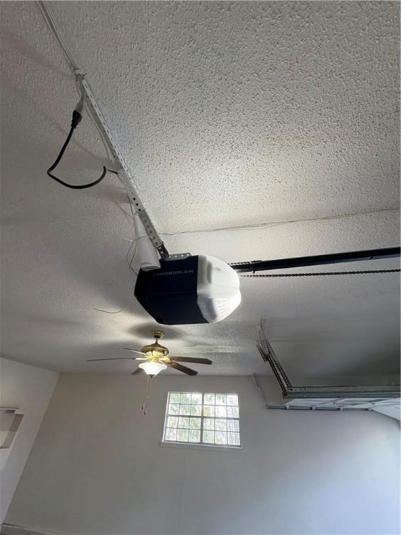 details with a garage door opener, a ceiling fan, and a textured ceiling