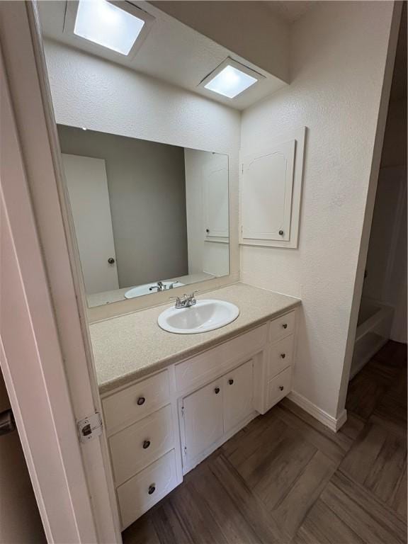 bathroom with a tub, vanity, and baseboards
