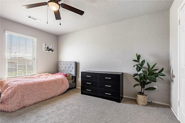 bedroom with carpet flooring, a textured wall, visible vents, ceiling fan, and baseboards