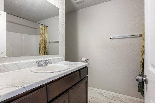 full bath with baseboards, vanity, and marble finish floor
