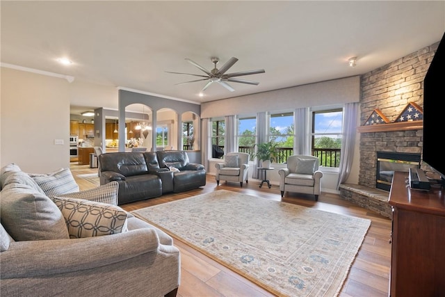 15 Serenity Ln, Holiday Island, AR 72631 - living area with a ceiling fan, a stone fireplace, wood finished floors, arched walkways, and ornamental molding