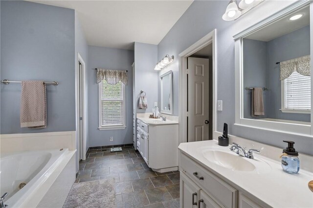 15 Serenity Ln, Holiday Island, AR 72631 - bathroom featuring plenty of natural light, stone finish flooring, two vanities, and a jetted tub