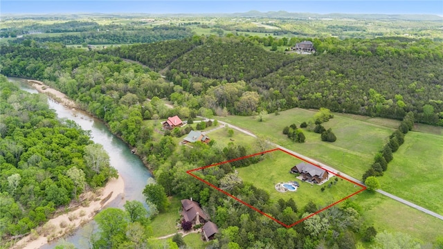birds eye view of property with a wooded view and a water view