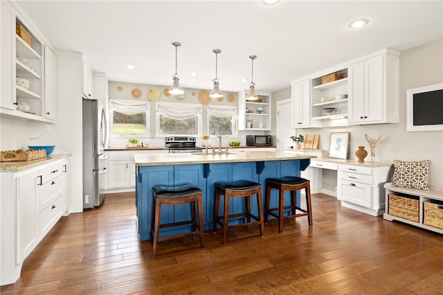 kitchen featuring stainless steel appliances, open shelves, white cabinets, a sink, and a kitchen breakfast bar
